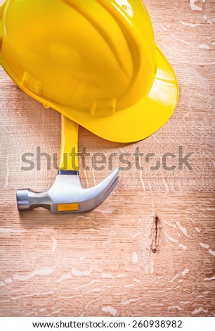 claw hammer and yellow helmet on wooden board construction concept