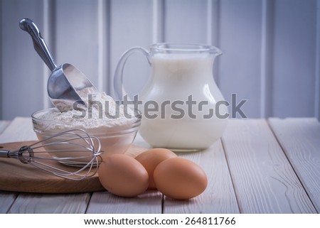 horizontal version corolla eggs flour bowl scoop pitcher milk on white painted old wooden board food and drink concept