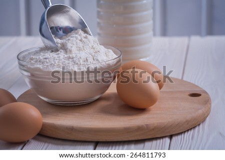 very close up view eggs flour in bowl scoop bottle of milk on white painted old wooden board food and drink concept