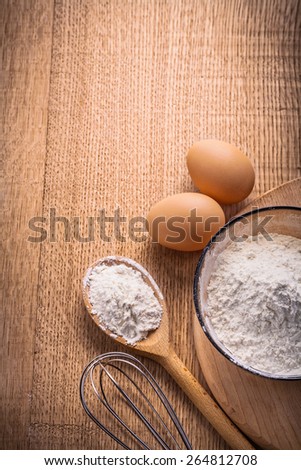vertical aerial view organized copyspace eggs flour in bowl spoon corolla on wooden board food and drink concept