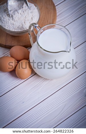 aerial view egg milk jug flour bowlon white painted wooden board food and drink still life