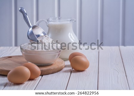 composition bowl with flour scop eggs milk in pitcher on white painted old wooden board food and drink concept