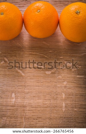 three orange fruits on wooden table with organized copyspace