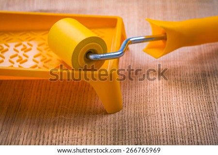 roller on paint tray and wooden board