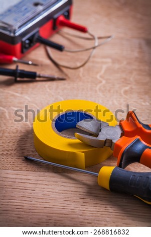 nippers screwdriver insulating tape multimeter On Wooden Board