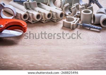 Big Set Polypropylene Fixators And  Pipes With Clips Pipe Cutter On Wooden Board