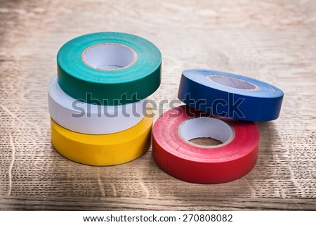green white yellow red blue rolls of insulating tape on wooden board construction concept