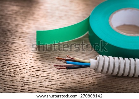 horizontal view roll of green insulating tape and electric cable in corrugated pipe