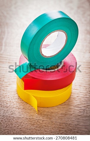 three rolls of insulating tape on wooden board close up  construction concept