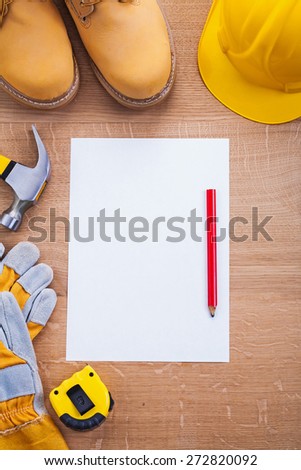 vertical version pencil paper helmet boots gloves hammer tapeline on wooden board organized copyspace