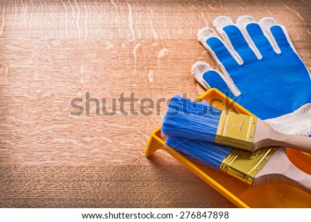Wooden board with protective gloves paint tray and brushes construction concept