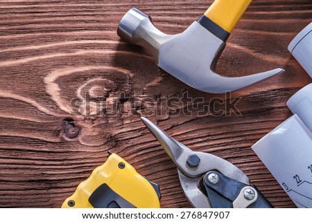 Claw hammer blueprints nippers and tape-measure on wood board construction concept