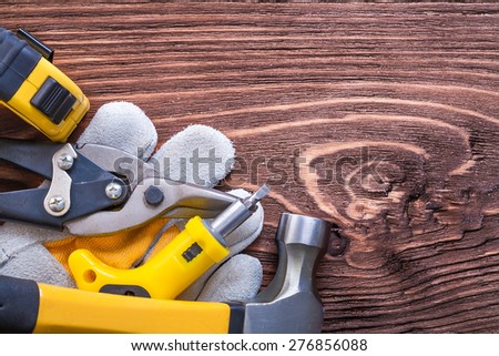 Tape-measure construction glove claw hammer screwdriver and wire-cutter on brown wooden board