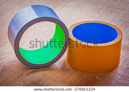 Rolls of duct tapes on vintage brown wooden board construction concept