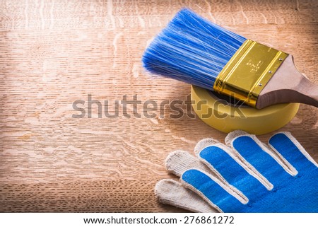 Safety gloves paint brush and duct tape on wooden board maintenance concept