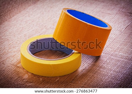 Narrow and wide duct tapes on vintage brown wooden board maintenance concept