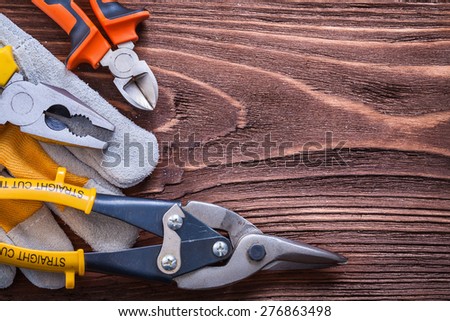 Nippers pliers wire-cutter and protective glove on wood board construction concept