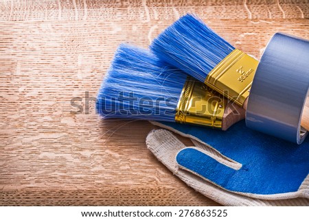 Paint brushes in duct tape on protective gloves construction concept