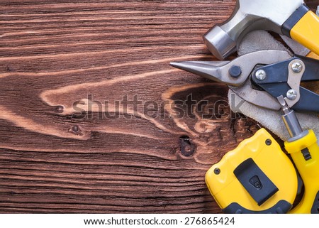 Hammer protective glove tape-measure screwdriver and nippers on wooden board