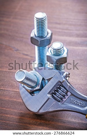 Brown wooden board with adjustable spanner metal threaded bolts and screw nuts construction concept