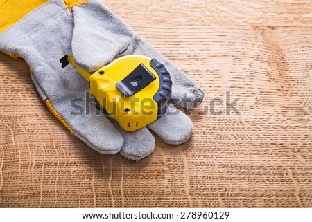 yellow construction tape measure obverse on side of the protective glove and wooden board