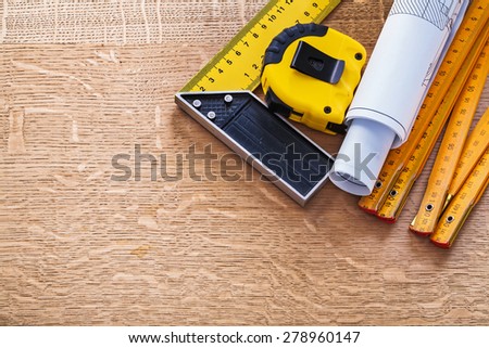 Blueprints square ruler tape measure and wooden meter on oak board construction concept