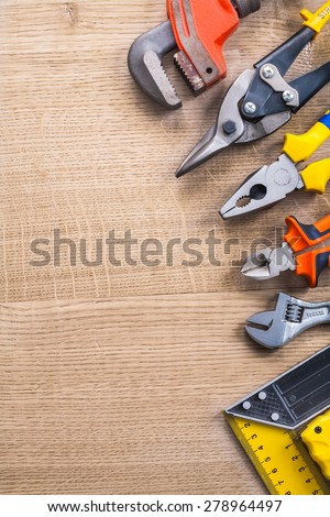 spanner cutter pliers nippers square ruler on wooden board with copyspace