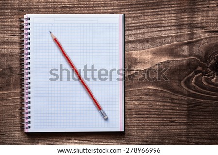 Clean squared copybook with pencil on pine brown wooden board education concept