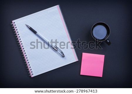Checked notepad pen sticky note and cup of coffee on black background education concept