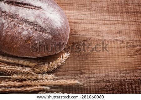 Bunch of wheat ears long loaf on oak wooden board food and drink concept