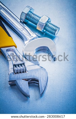 Adjustable spanner open-end wrench bolt and nut on metallic background construction concept