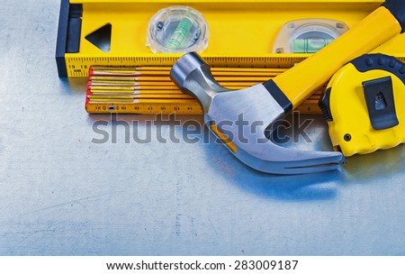 Horizontal view of construction level tape line claw hammer wooden meter on metallic background maintenance concept