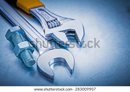 Stainless adjustable spanner open-end wrench bolt and nut on metallic background construction concept