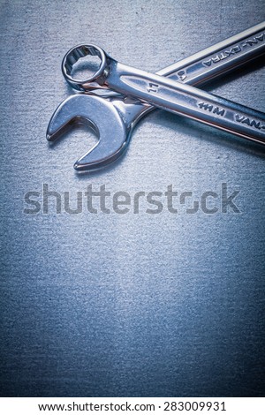 Stainless flat spanner and hook wrench on metallic background construction concept