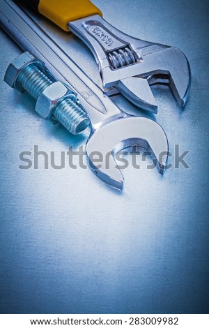 Metal adjustable spanner open-end wrench bolt and nut on metallic background repairing concept