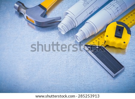 Construction drawings tape measure square ruler and claw hammer on industrial metallic background maintenance concept