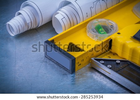 Construction drawings and level tape measure square ruler on metallic background close up view maintenance concept.