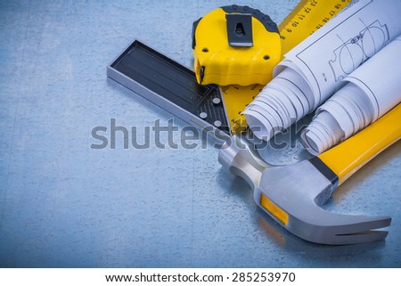 Metallic background with blueprints claw hammer square ruler and measuring tape construction concept