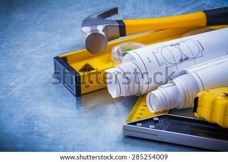 Close up image of hammer measuring line construction plans and level square ruler on metallic background maintenance concept.