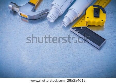 Construction plans measuring line square ruler and claw hammer on industrial metallic background maintenance concept