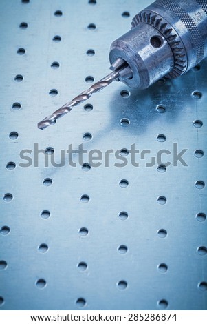 Metal drill on perforated metallic sheet construction concept.