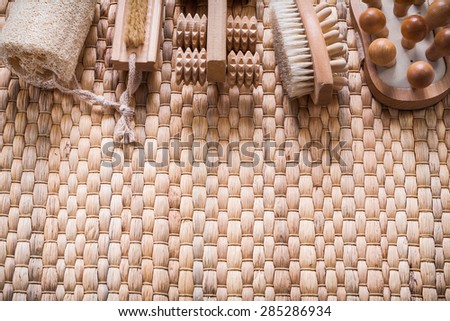 Scrubbing brush wooden massagers and loofah on wicker background healthcare concept