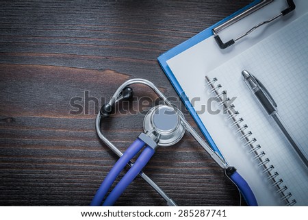 Clip board copybook pen and stethoscope tablet on vintage wooden background medicine concept