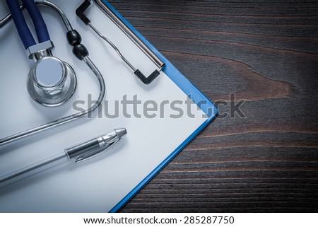 Clip board pen and stethoscope tablet on vintage wooden background medicine concept