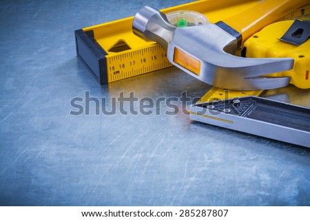 Horizontal version of claw hammer tape measure construction level square ruler on metallic background maintenance concept.