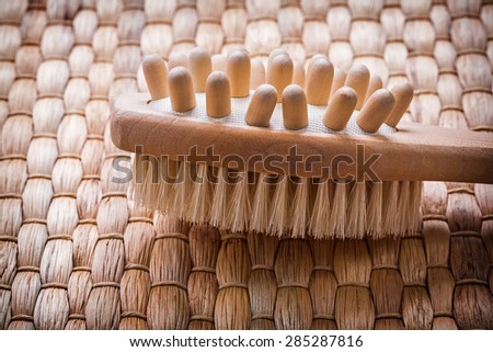 Close up image of wooden massager with scrubbing brush on wicker background healthcare concept