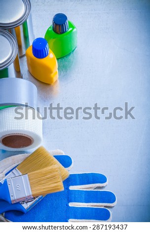 Paint cans bottles brushes duct tapes and safety gloves on metallic background maintenance concept.