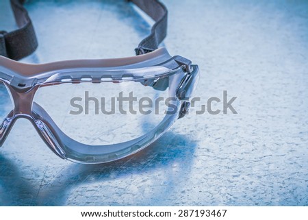 Plastic safety glasses on metallic background construction concept.