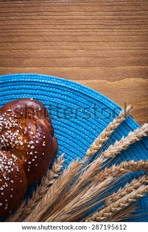 Sweet roll wheat rye ears with blue wicker cloth on wooden board food and drink concept.