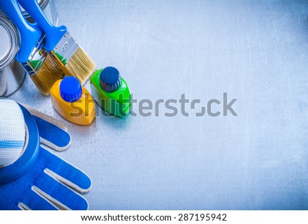 Copy space image of paint cans bottles brushes household tapes and protective gloves on metallic background construction concept.